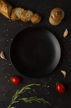 boş siyah tabak ve taze baharat, kaşık ve sebze malzemeleri, üst manzara.