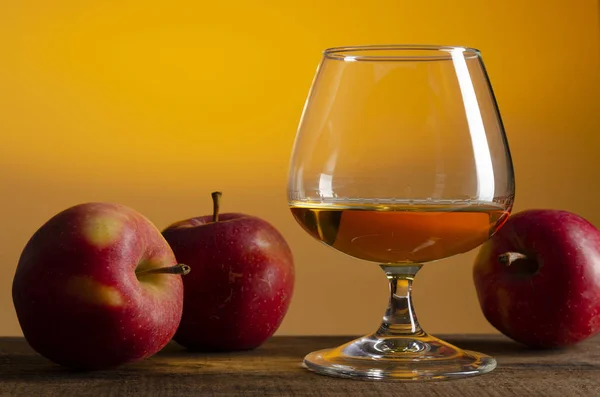 Glas Calvados Brandy en rode appels op houten tafel — Stockfoto