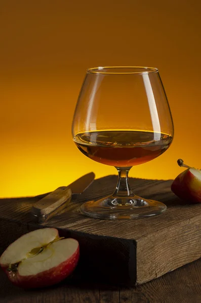 Glas Calvados Brandy en rode appels op houten tafel — Stockfoto