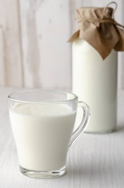 Ahşap masanın üstünde ekmek rulosu olan kefir şişesi.