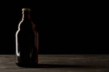 Bira şişesi siyah arka planda ve bir bardak birayla