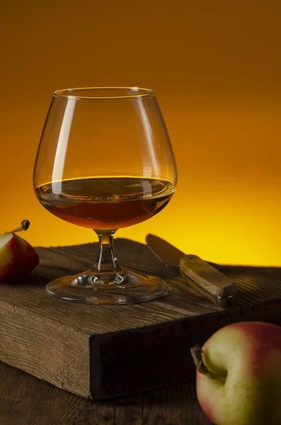 Glas Calvados Brandy en rode appels op houten tafel — Stockfoto