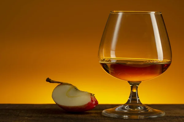 Glas Calvados Brandy en rode appels op houten tafel — Stockfoto