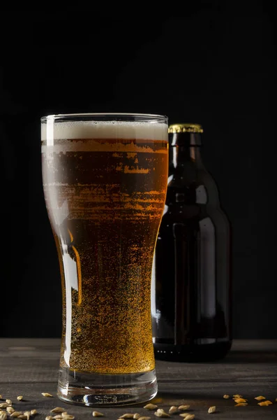 Beer bottle on black background with glass of beer — Stock Photo, Image