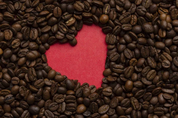 Red heart from coffee beans on coffee background — Stock Photo, Image