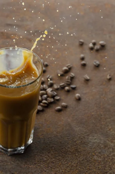 Splash de bebida de café gelado em um fundo marrom. Iatte com gelo . — Fotografia de Stock