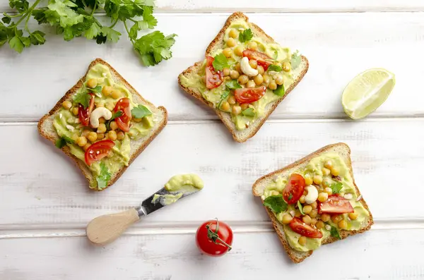 Vegan sandwich with avocado, nuts, vegetables and olive oil on white wooden