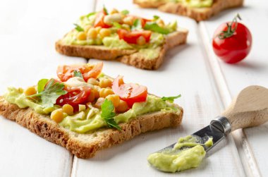 Avokado, fındık, sebze ve beyaz ahşap masada zeytinyağlı vejetaryen sandviç.