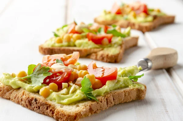 Sandwich vegano con aguacate, nueces, verduras y aceite de oliva sobre mesa de madera blanca — Foto de Stock