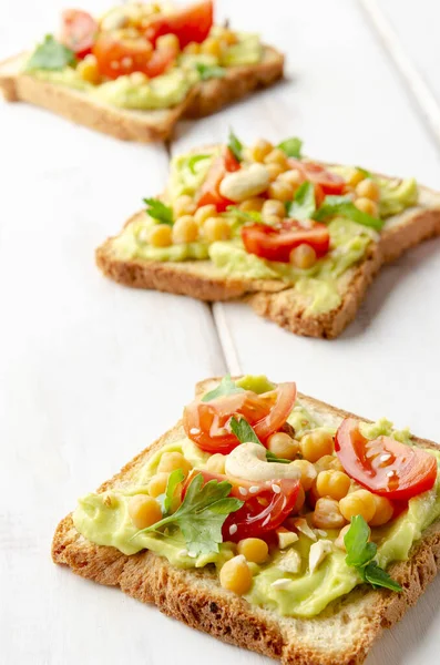 Vegan sandwich with avocado, nuts, vegetables and olive oil on white wooden