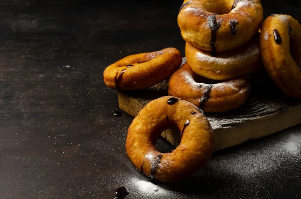 Donuts sprinkled with powdered sugar on dark background — Stock Photo, Image