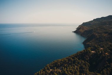 Mayorka 'nın Hilly Sahili. Arka planda denizde küçük bir tekne. Yaz manzarası.