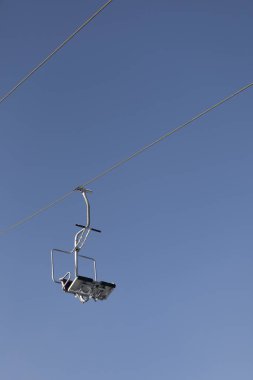 People are lifting on ski-lift in the mountains. Beautiful, sunny and windy weather.