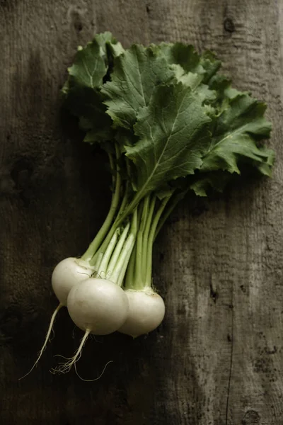 Nabos orgánicos rústicos con tapas verdes frescas y raíces sobre fondo de madera genuina. comida vegetariana, enfoque selectivo —  Fotos de Stock