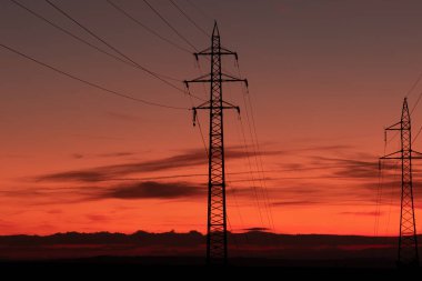 Gün doğumunda Moravya sahasında yüksek voltaj hatları ve iletim kuleleri silueti