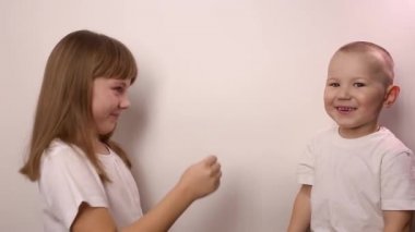 Mutlu çocuklar beyaz arka planda taş kağıt oyunu oynar, gülümser ve güler.