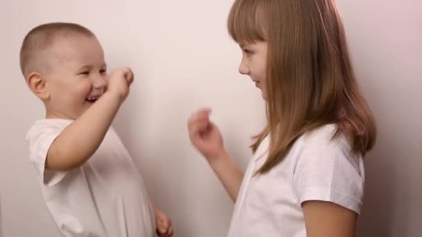 Niños felices jugar juego piedra papel tijera sobre fondo blanco, sonrisa y risa — Vídeos de Stock