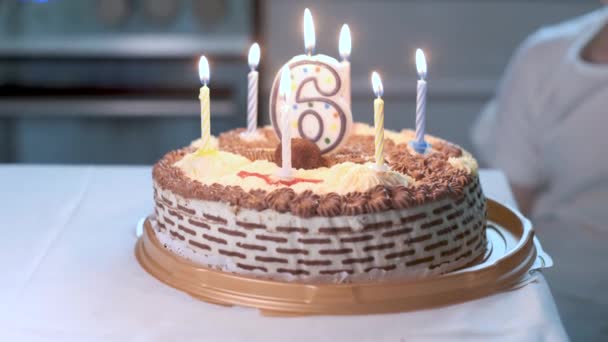 Primer plano en pastel de cumpleaños con vela encendida en forma de número seis en él — Vídeos de Stock