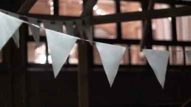 Beyaz üçgen bayraklar dışarıda asılı ve akşam rüzgarda sallanıyor. Gece şenliği sahnesi. Kutlama ya da geç parti konsepti. Tatil için arka bahçenin dekorasyonu. arkaplandaki pencere