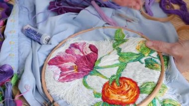 Vitiligo iğneli kadın elleri. Nakışlı halka, mavi işlemeli kumaş renkli desenli. Düz yatış, üst manzara, yakın çekim. Geleneksel hobi, yaşam tarzı. İğne işi, el işi.