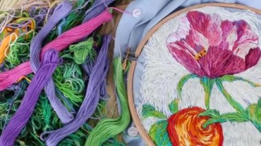 Renkli güzel desenli mavi işlemeli kumaşın arka planında nakışlı halkalar ve iğnelerin bileşimi. Düz yerde, üst tarafta. Geleneksel hobi. Dikiş için hazırlanılıyor