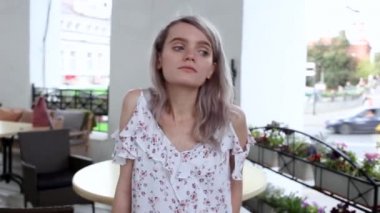 Yazlık elbiseli, kafede oturan ve poz veren güzel bir kıza yakın çekim.