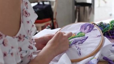 Genç kadın elleri iğneyle dikilir. Dikiş, nakış, hobi. Yakın çekim.