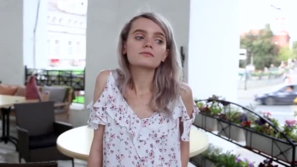 Close-up op jong mooi meisje in de zomer jurk zitten in cafe en poseren — Stockvideo