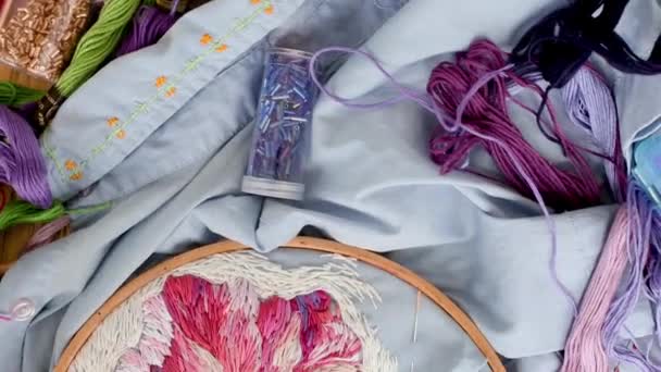 Embroidery hoops, threads, needles on embroidered fabric with colorful pattern — ストック動画