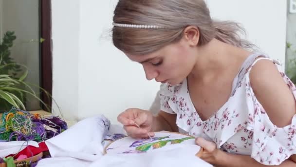 Schattig meisje aan tafel naaien met naald. borduurwerk, borduurwerk, hobby, handwerk — Stockvideo