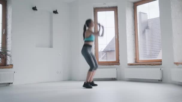 Vonzó fiatal fitt sportos lány sportruházat ugrás, hogy deszka otthon — Stock videók