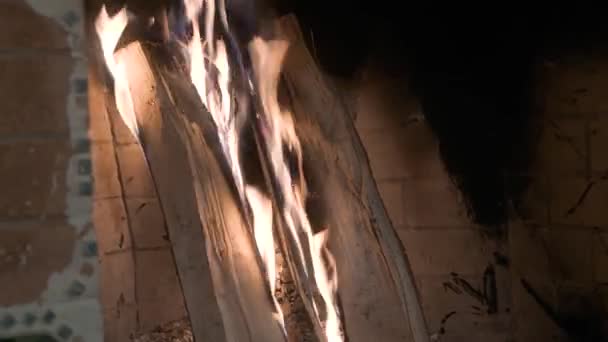 Stos drewna płonie w kominku z cegły. języki płomienia żółtego i fioletowego — Wideo stockowe