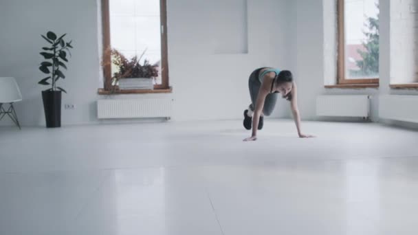 Привлекательная молодая девушка в спортивной одежде бегает доску в светлой комнате дома — стоковое видео