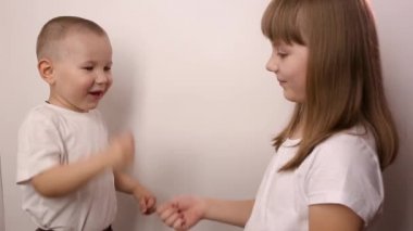 Mutlu çocuklar beyaz arka planda taş kağıt oyunu oynar, gülümser ve güler.