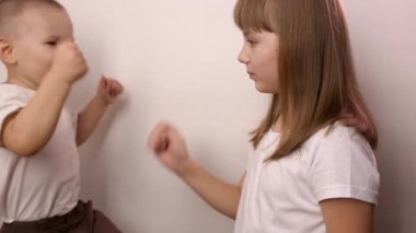 Mutlu çocuklar beyaz arka planda taş kağıt oyunu oynar, gülümser ve güler.