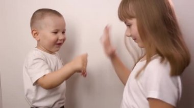 Mutlu çocuklar beyaz arka planda taş kağıt oyunu oynar, gülümser ve güler.