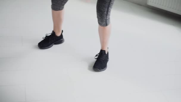Primer plano en las piernas de la deportista en zapatillas de deporte haciendo ejercicios. fitness, pérdida de peso — Vídeos de Stock