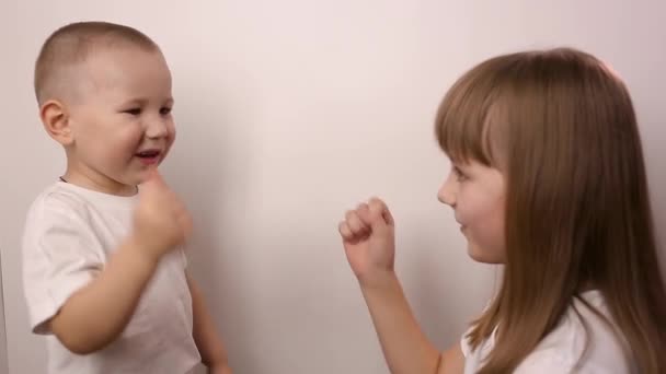 Heureux enfants jouer jeu pierre ciseaux de papier sur fond blanc, sourire et rire — Video