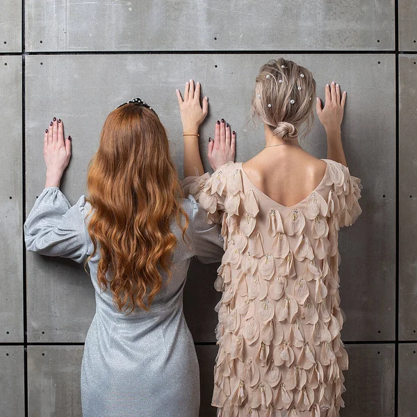 Duas raparigas de pé contra a parede, vista traseira. fêmeas inclinar as mãos na parede — Fotografia de Stock