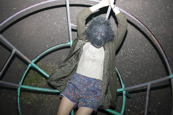 Kaukasisches Mädchen mit Gorillamaske liegt auf Metallkonstruktion von Spielplatz — Stockfoto