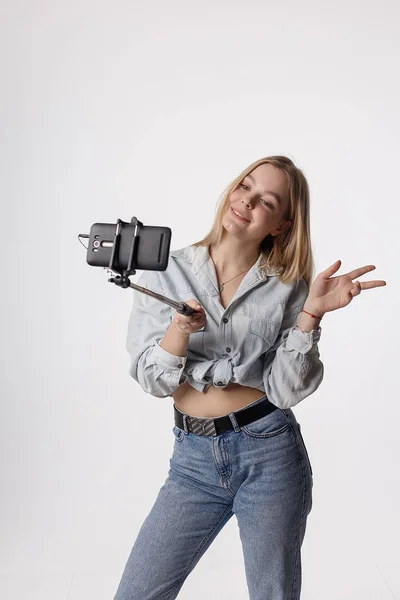 Χαρούμενη νεαρή κοπέλα κάνοντας αυτο πορτρέτο με το smartphone που συνδέονται με selfie ραβδί — Φωτογραφία Αρχείου