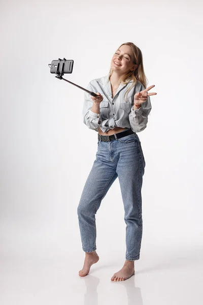 Gelukkig jong meisje het maken van zelfportret met smartphone bevestigd aan selfie stick — Stockfoto
