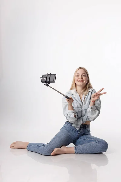 Mutlu genç kız, selfie çubuğuna bağlı akıllı telefonuyla kendi portresini yapıyor. — Stok fotoğraf