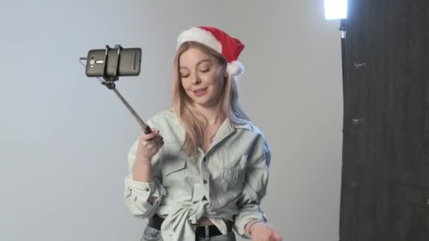 Kadın kozmetik inceleme videosu ve selfie çubuğuna bağlı akıllı telefon. — Stok video