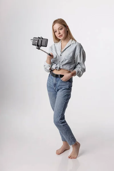 Feliz chica joven haciendo autorretrato con teléfono inteligente conectado al palo selfie —  Fotos de Stock
