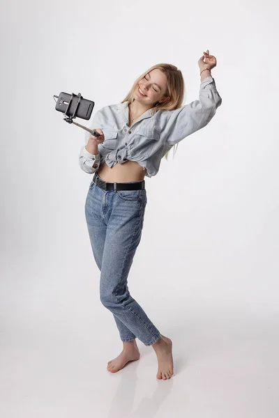Χαρούμενη νεαρή κοπέλα κάνοντας αυτο πορτρέτο με το smartphone που συνδέονται με selfie ραβδί — Φωτογραφία Αρχείου