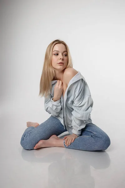 Sexig kaukasiska flicka poserar i blå jeans och skjorta på vit studio bakgrund — Stockfoto