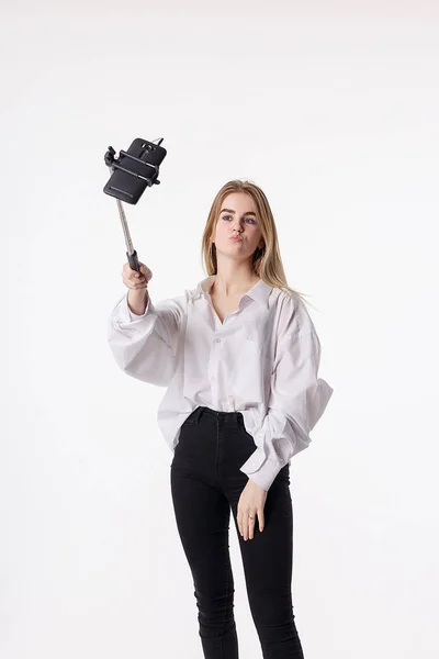 Glad ung flicka gör själv porträtt med smartphone ansluten till selfie stick — Stockfoto