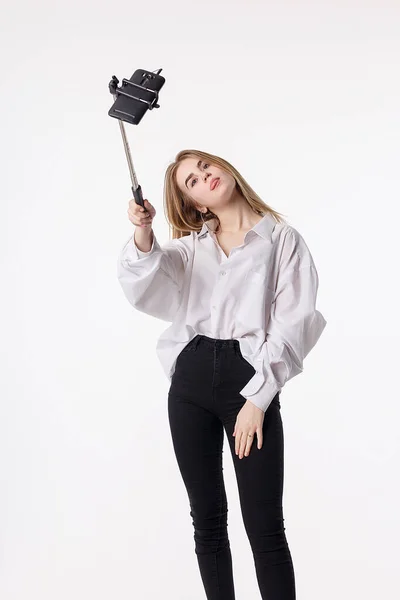 Young pretty girl making self portrait with smartphone attached to selfie stick — 스톡 사진