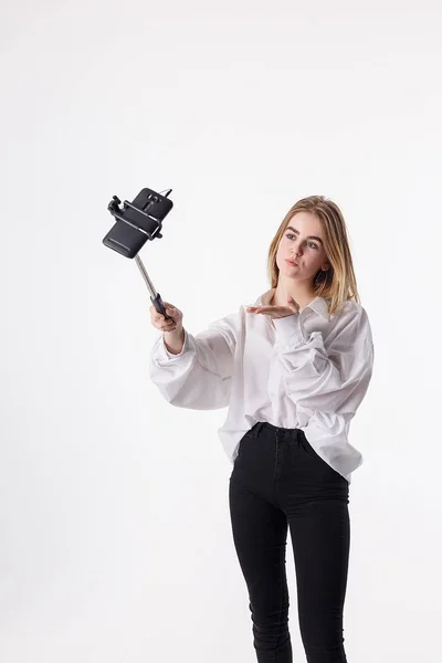 Ung söt flicka gör själv porträtt med smartphone ansluten till selfie stick — Stockfoto